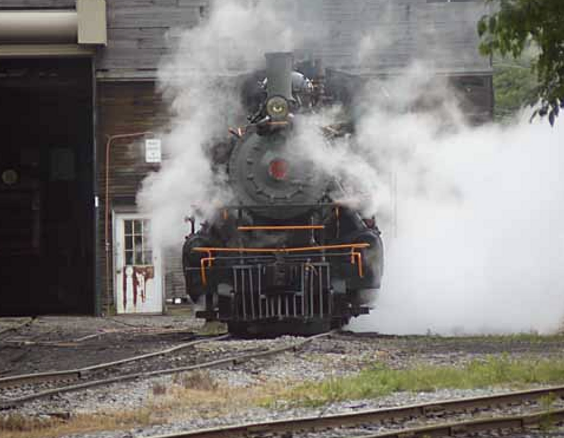 a steam engine on a train track with smoke coming out of it